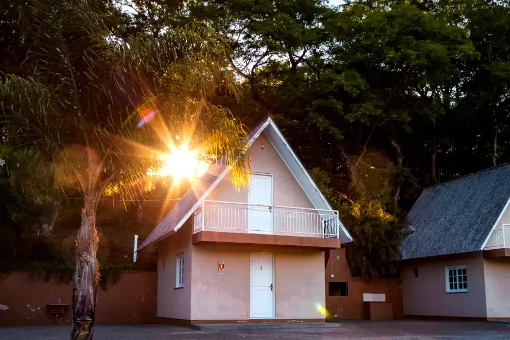 Cabana com sacada ao entardecer, entre palmeiras