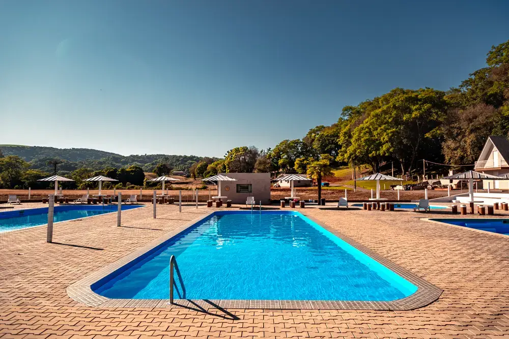 Piscina adulto com borda de pedra e céu azul